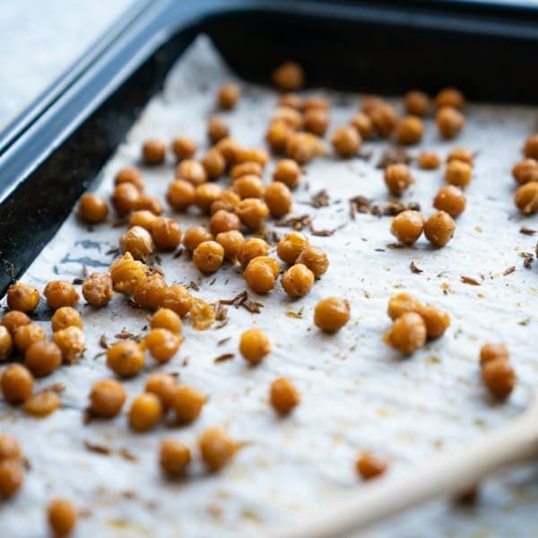 Crisp roasted chickpeas spread on a baking sheet with a wooden spoon.